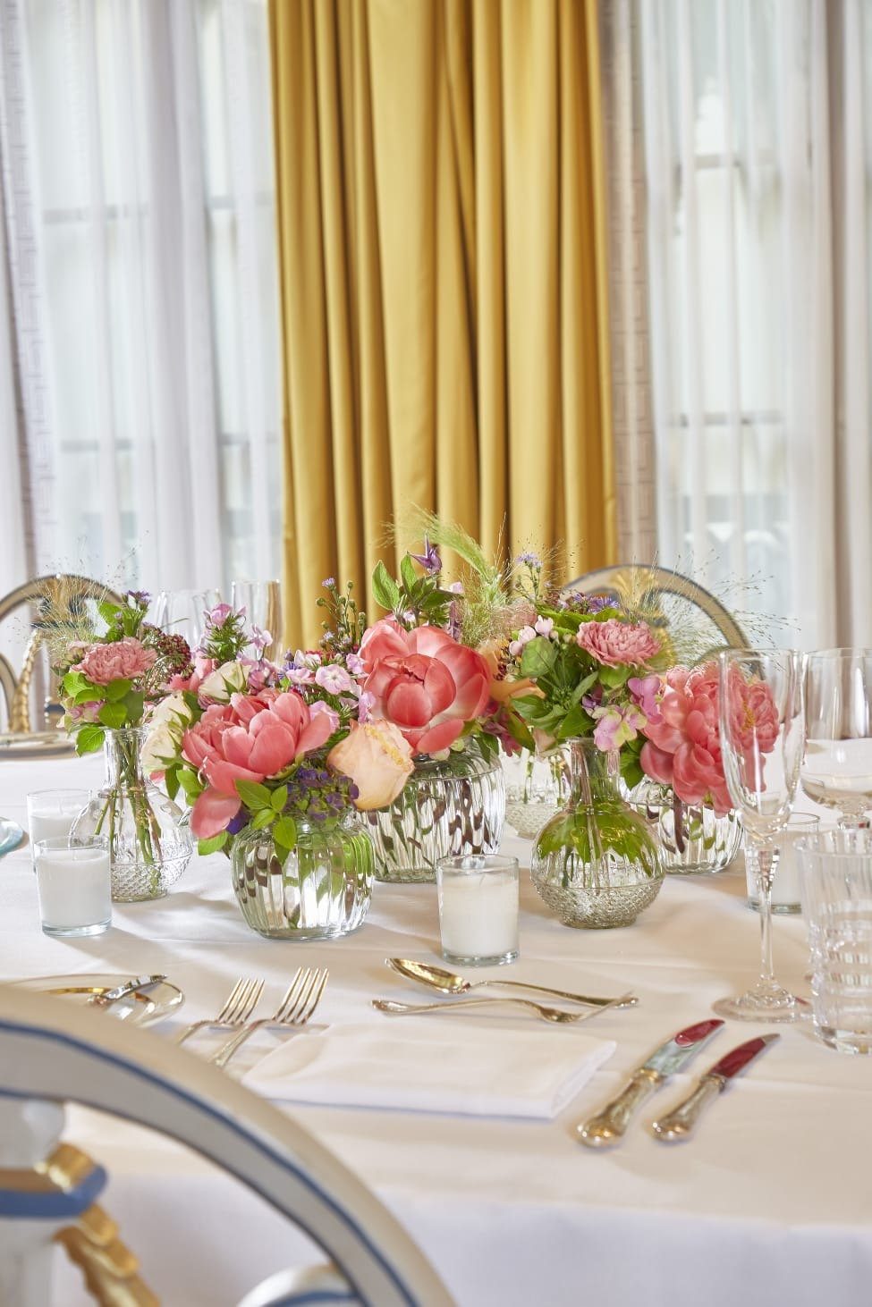 Dining table styled with small bud vases and white linens