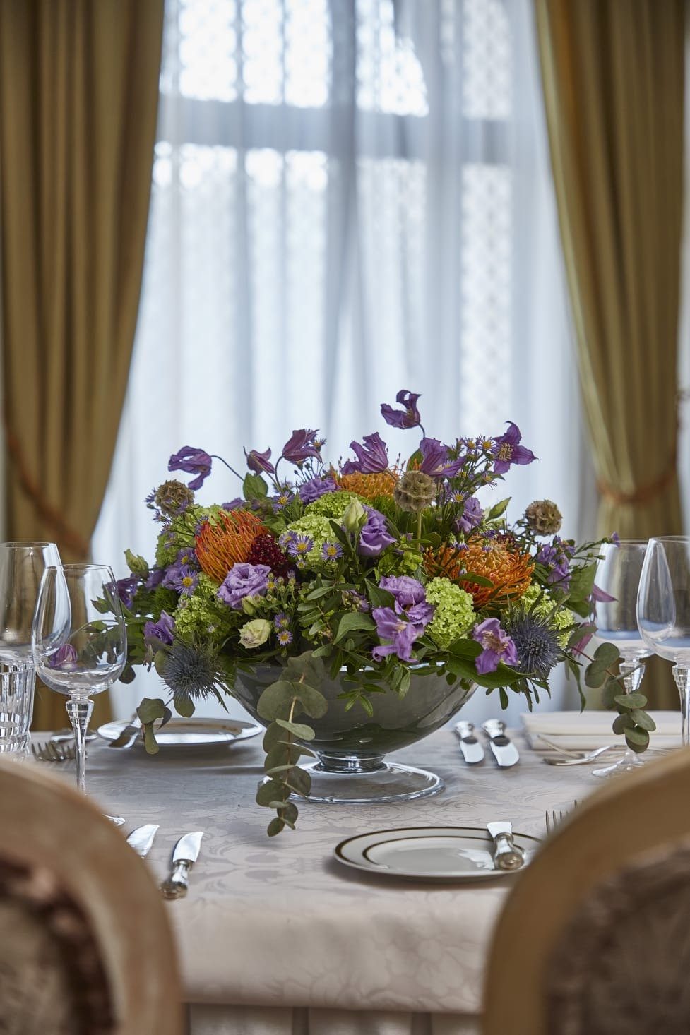 Purple, orange and green floral centrepiece on a dining table