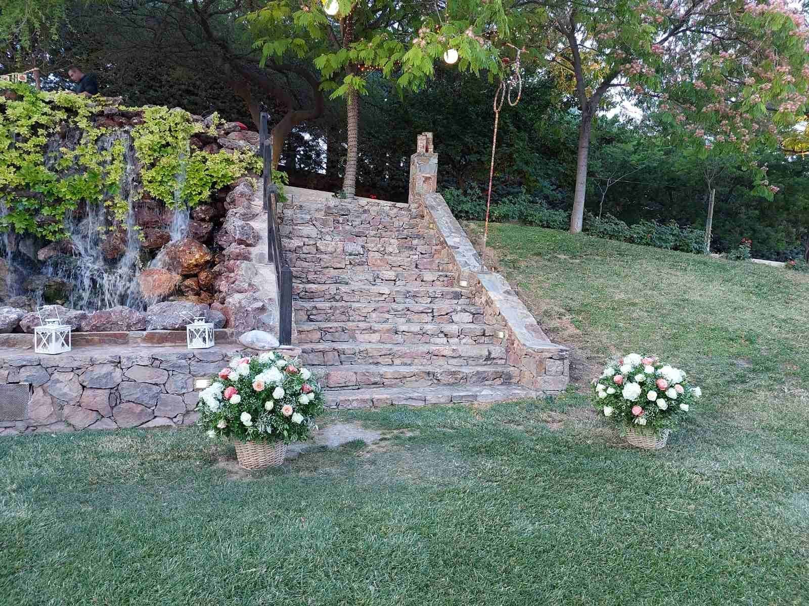 Two white floral arrangements placed at the foot of stone stairs in daylight